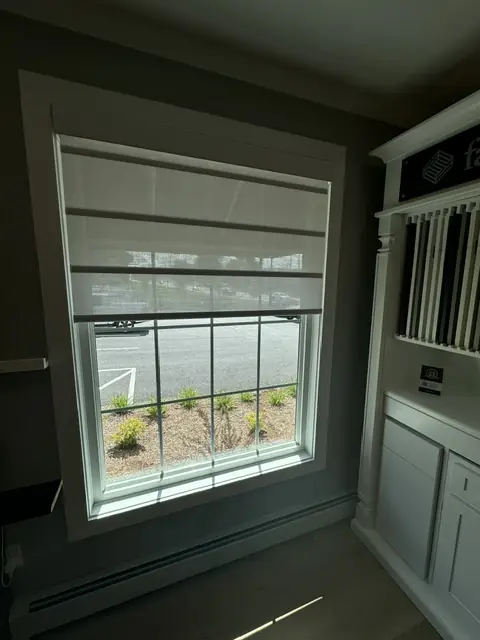 Light fabric shade on a window framed in dark trim