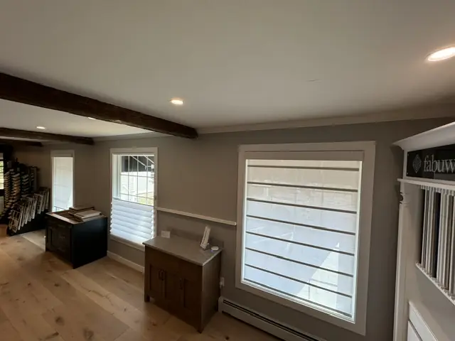 White shade on a den window under dark ceiling beams