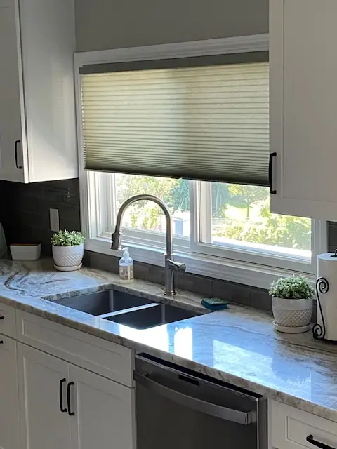 Cellular shade half-raised over a kitchen sink window