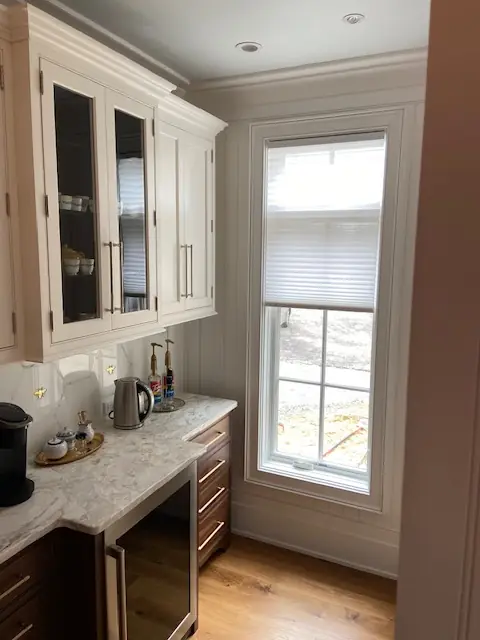 Light cellular shade on a window beside white built-in cabinets
