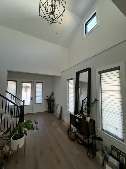 Shades on the windows of a bright two-story entry with a staircase